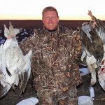 Hunter with a handful of harvested snow and blue geese.