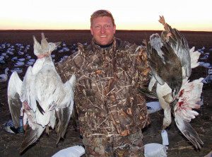 Hunter with a handful of harvested snow and blue geese.